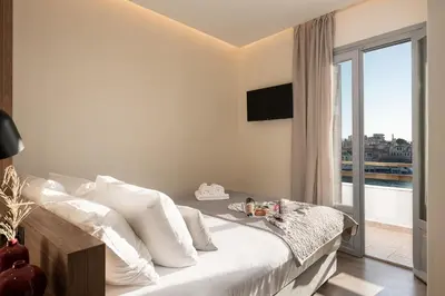 a bedroom with a bed with white pillows and a window at Amphitrite Hotel in Chania Town