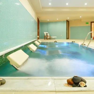 an indoor pool with blue water in a building at Giannoulis – Cavo Spada Luxury Sports & Leisure Resort & Spa in Kolymvari