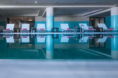 a swimming pool with white chairs in a building at Giannoulis – Cavo Spada Luxury Sports & Leisure Resort & Spa in Kolymvari