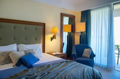 a hotel room with a bed and a blue chair at Giannoulis – Cavo Spada Luxury Sports & Leisure Resort & Spa in Kolymvari