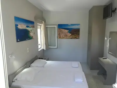 a white bedroom with a bed and a window at Niriis Hotel in Kato Daratso
