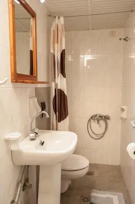 a bathroom with a sink and a toilet and a mirror at Niriis Hotel in Kato Daratso