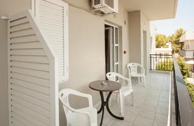 a patio with white chairs and a table on a balcony at Niriis Hotel in Kato Daratso
