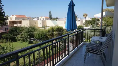 a balcony with an umbrella and a chair and an umbrella at Niriis Hotel in Kato Daratso