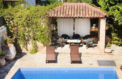 a patio with a table and chairs and a swimming pool at Potoula Apts in Kato Daratso