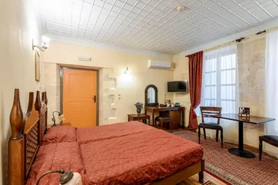 a bedroom with a red bed and a desk and a table at Belmondo Hotel in Chania Town