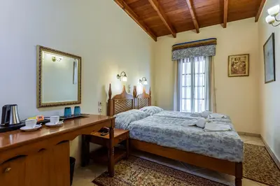 a bedroom with a bed and a desk and a mirror at Belmondo Hotel in Chania Town