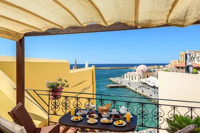 a table with food on a balcony with a view of the water at Belmondo Hotel in Chania Town