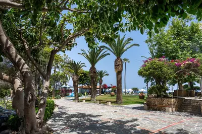 a walkway with palm trees in a park at Leptos Panorama Hotel in Kalamaki Chanion