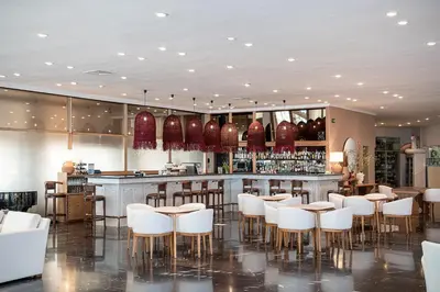 a bar in a restaurant with white chairs and a counter at Leptos Panorama Hotel in Kalamaki Chanion