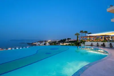 a swimming pool with a view of the ocean at night at Leptos Panorama Hotel in Kalamaki Chanion