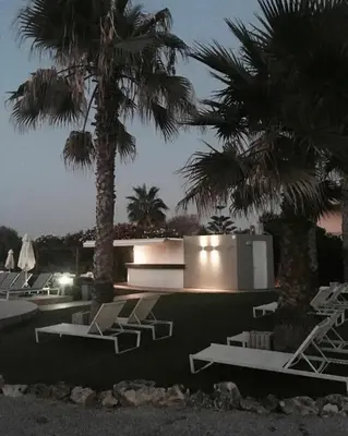 a pool with lounge chairs and palm trees at night at Phaedra Hotel in Stalos