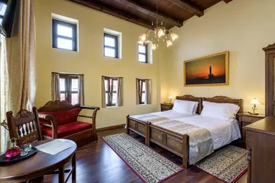 a bedroom with a bed and a chair and a table at Porto Del Colombo Traditional Boutique Hotel in Chania Town