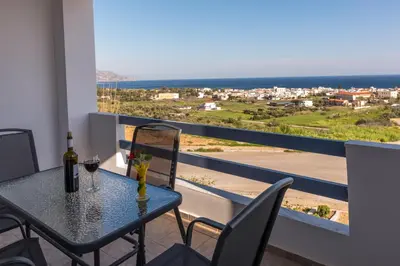 a table with a glass of wine on a balcony at Roula Apartments in Palaiochóra