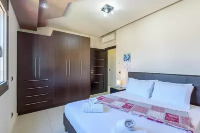 a bedroom with a large bed with a brown cabinet at Evgenias Luxury Apartment with Rooftop Pool in Chania Town