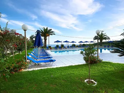 a swimming pool with blue lounge chairs and umbrellas at Eleftheria Hotel in Agia Marina Nea Kydonias