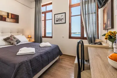 a bedroom with a bed and a table and windows at Villa Venezia in Chania Town