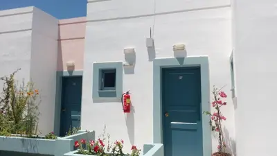 a white building with two blue doors and flowers at Hotel Kleopatra in Stalos