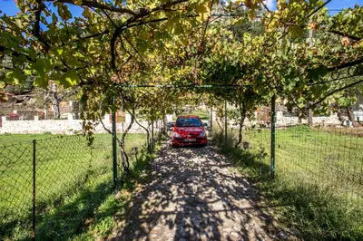 a red car parked on a dirt road next to a fence at Ifigenia Lux MAISONETTE in oldtown and Villas in theriso vilage 14 km outside of chania in Chania Town