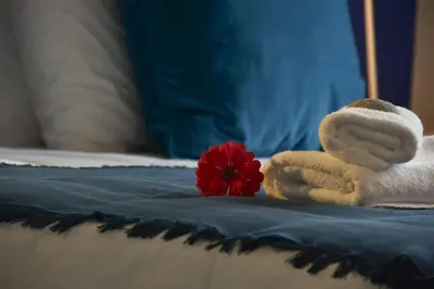a couple of towels and a red flower on a bed at GT Beach in Maleme