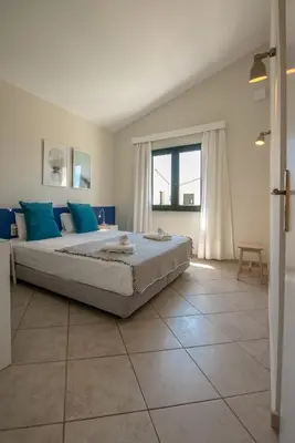 a bedroom with a large bed with blue pillows at GT Beach in Maleme
