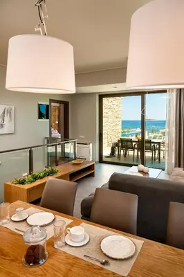 a living room with a dining table and a view of the ocean at Eland Dream Villas in Kalamaki Chanion
