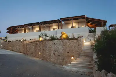 a house with a stone wall and stairs with lights at Popy's Place in Kato Daratso