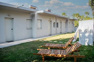 a wooden bench sitting in the grass in front of a building at Popy's Place in Kato Daratso