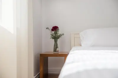 a vase of flowers sitting on a table next to a bed at Thea Thalassa in Kalamaki Chanion