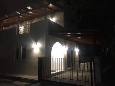a house lit up at night with a gate and lights at The Endless Blue Maisonette in Palaiochóra
