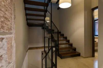 a black spiral staircase in a home with a stone wall at Nonnalena Boutique Hotel in Chania Town