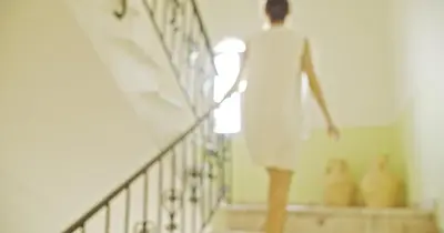 a woman walking down the stairs in a white dress at Waterlily Hotel Apartments in Kalathas