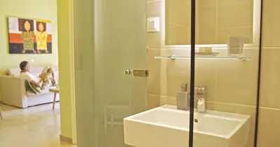 a bathroom with a sink and a person sitting on a couch at Waterlily Hotel Apartments in Kalathas