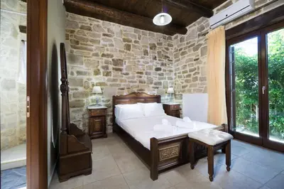 a bedroom with a bed and a stone wall at Cozy Stone Villa in Plátanos