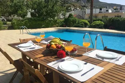 a wooden table with a bowl of fruit and wine glasses at Cozy Stone Villa in Plátanos