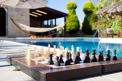 a chess board on a table next to a pool at Cozy Stone Villa in Plátanos