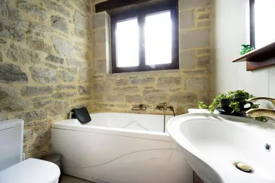 a bathroom with a white tub and a sink at Cozy Stone Villa in Plátanos