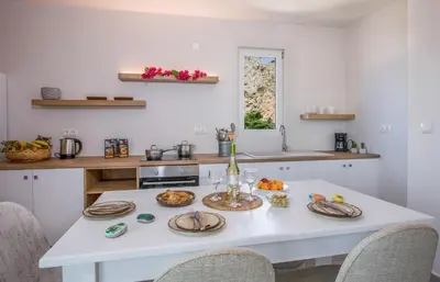 a kitchen with a white table with plates of food on it at Eleana Nature & Art in Khóra Sfakíon