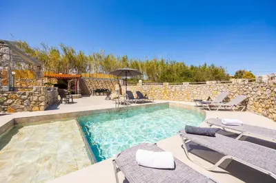 a swimming pool with two lounge chairs and an umbrella at Villa Melina in Tavronitis
