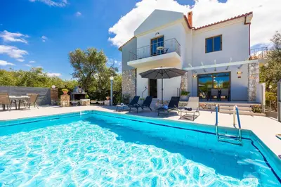 a villa with a swimming pool and a house at Villa Tzina in Plataniás
