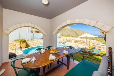 a dining room with a table and chairs and a pool at Villa Neria in Áptera