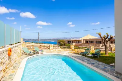 a swimming pool with chaise lounge chairs next to a house at Villa Neria in Áptera