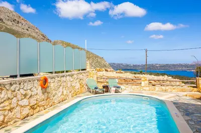a swimming pool with a stone wall and a rock wall at Villa Neria in Áptera