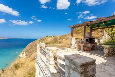 a stone patio with a grill next to the ocean at Souda Bay View in Kalami