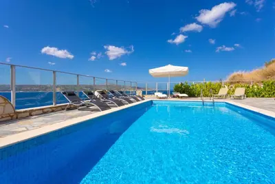 a swimming pool with chairs and a view of the water at Souda Bay View in Kalami