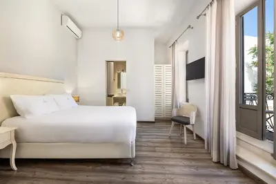 a bedroom with a white bed and a balcony at Shalom Luxury Rooms Daliani in Chania Town