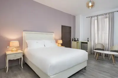 a white bedroom with a white bed and a table at Shalom Luxury Rooms Daliani in Chania Town