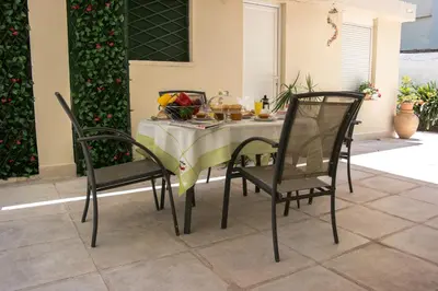 a table with two chairs and a table with fruit on it at Alexandra Apartment Near Chania Center in Chania Town