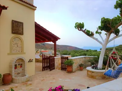 a house with a patio with a fireplace and a tree at Villa Athina in Kissamos