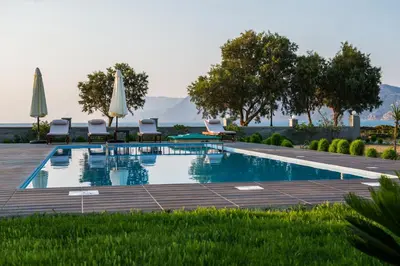 a swimming pool with lawn chairs and umbrellas at Niovi Seaside Suites in Kissamos